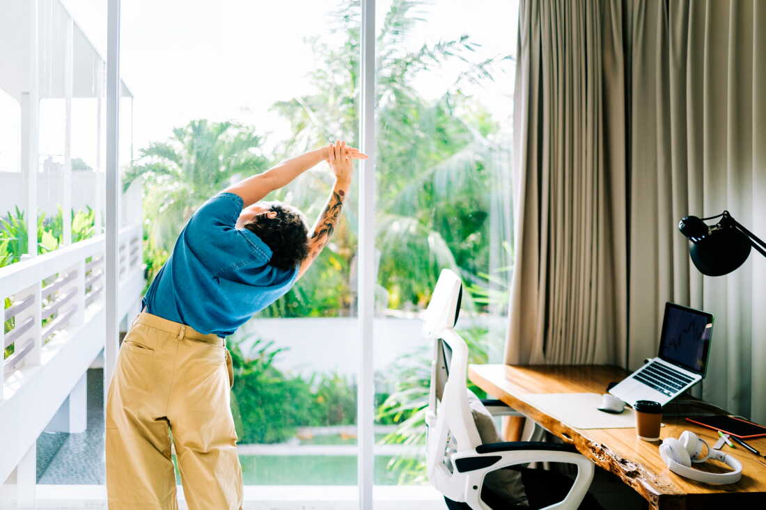 Woman demonstrating a side stretch during work break at home office.