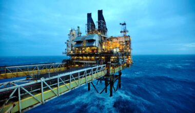 Offshore oil rig platform with illuminated facilities and a long gangway over choppy North Sea waters.