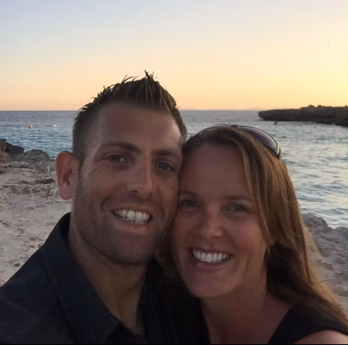 A smiling couple on a beach at sunset