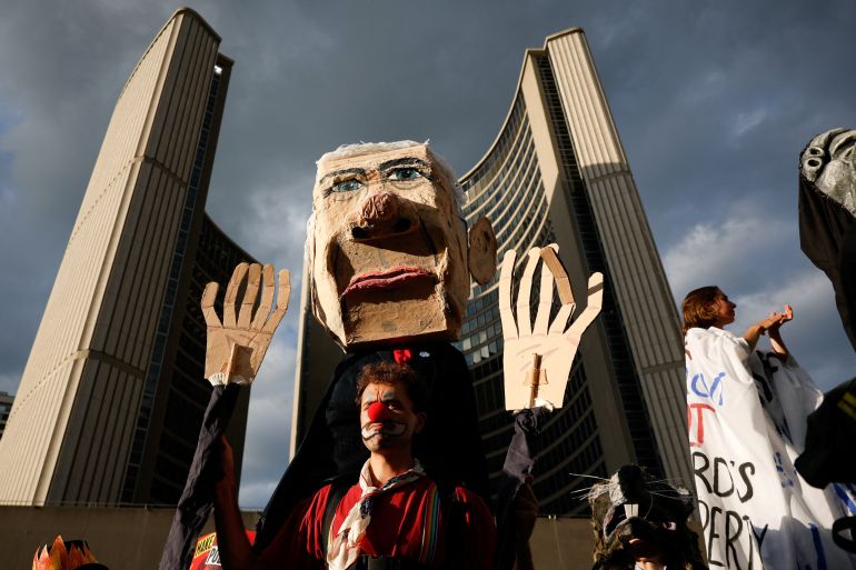 A protester carries an effigy depicting Canada's Prime Minister Mark Carney, as protesters gather at Nathan Philips Square in Toronto, Canada