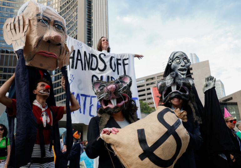 A protester carries an effigy depicting Canada's Prime Minister Mark Carney, next to demonstrators wearing rat costumes,