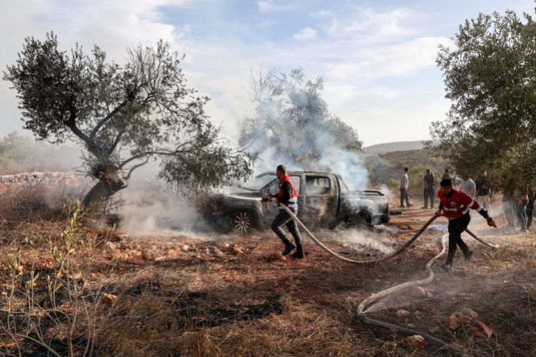 Firefighters douse a burned car with water after Israelis from illegal settlements attacked a group of Palestinians harvesting olives near Turmus Aya in the Israeli-occupied West Bank, on October 16, 2026