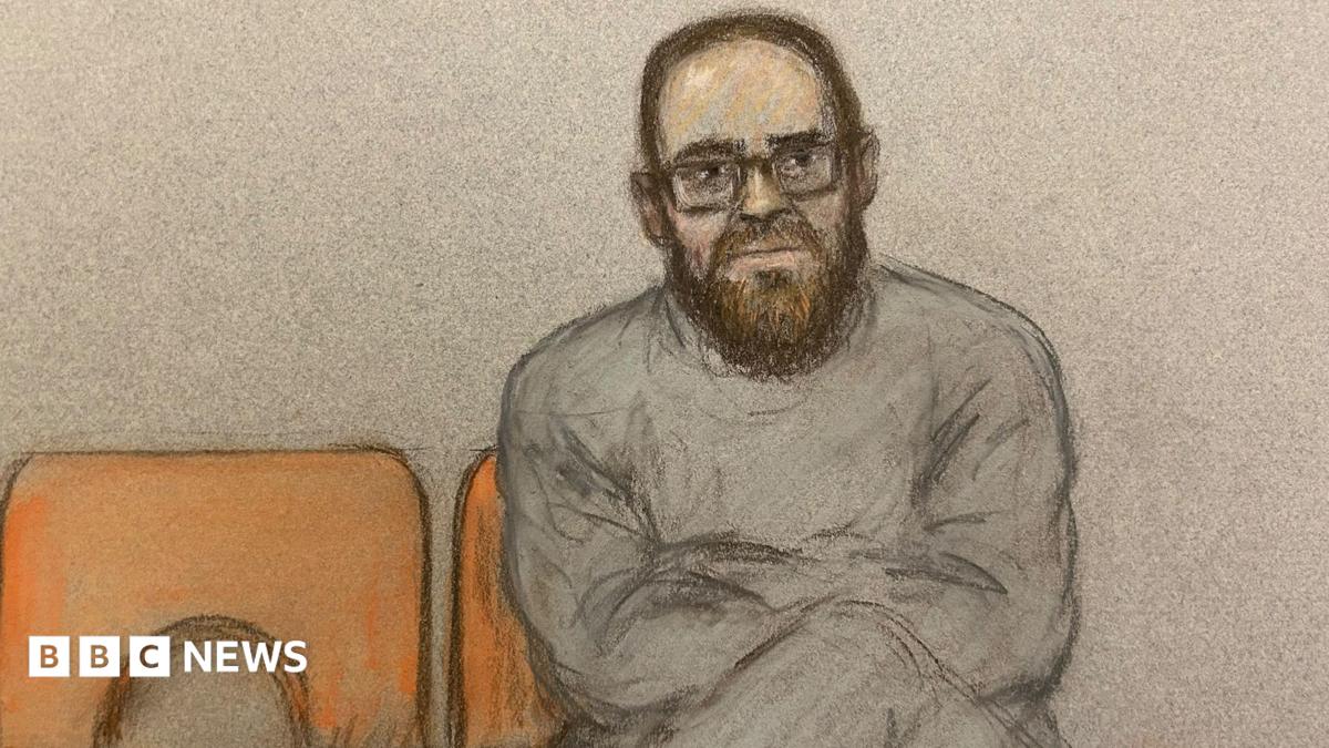 A court sketch of Joshua Kerry. He sits with his legs and arms crossed on an orange chair. He is wearing glasses and a grey tracksuit.