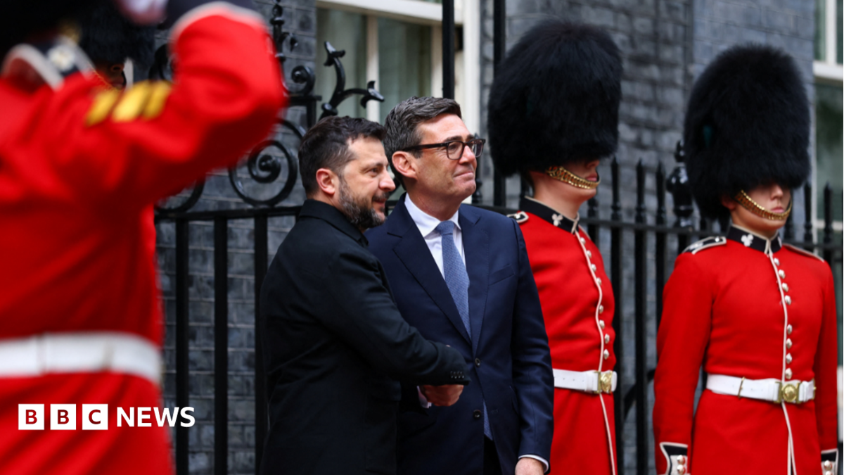 MI5 chief Sir Ken McCallum has short dark hair, dark glasses and is wearing a dark suit with a green tie.