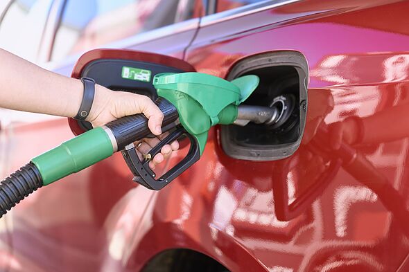 Close-up of a woman standing at a gas station filling her car with gasoline.