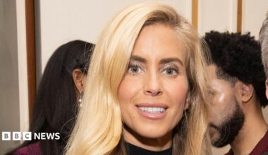 Woman with long blonde hair and pink lipstick and black turtleneck