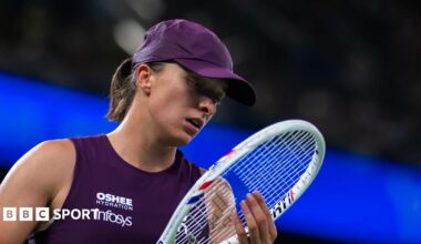 Iga Swiatek, in purple sleeveless tennis top and purple cap, looks at her racquet during a Wuhan Open semi-final defeat