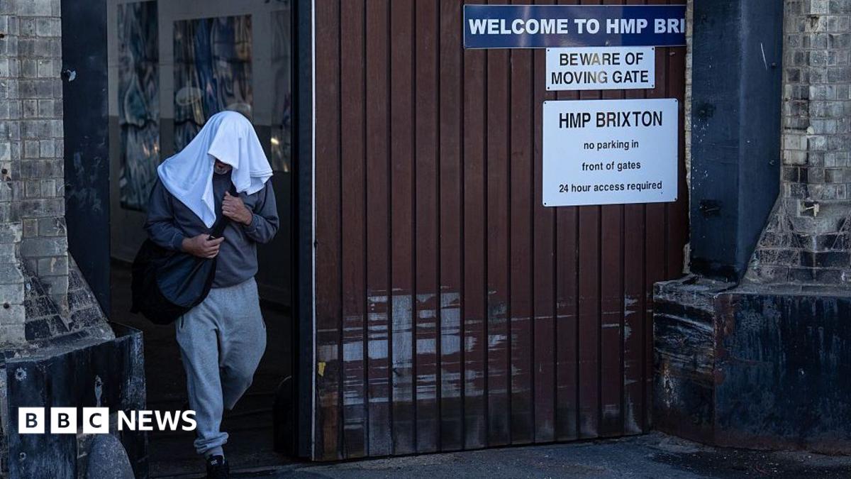 An inmate walks free from HMP Brixton with a while towel over his head