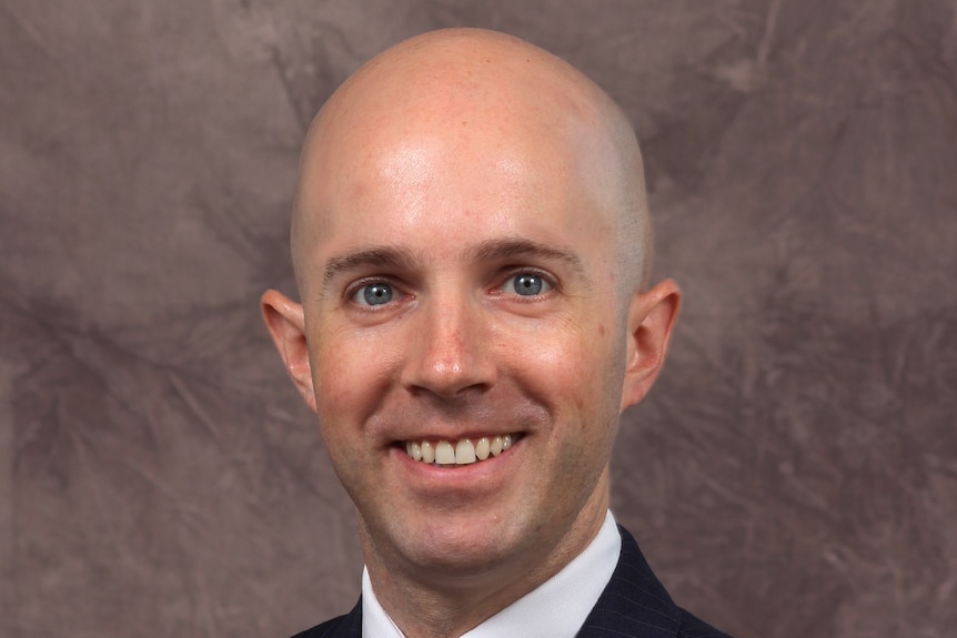 A photo of a bald man wearing a business suit.