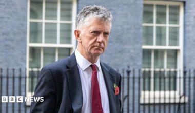 Jonathan Powell outside 10 Downing Street wearing a suit and tie.