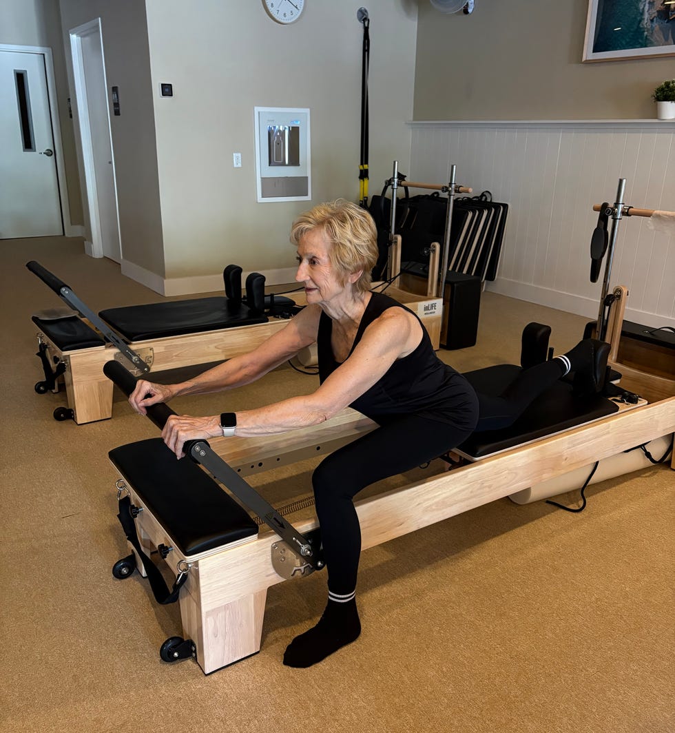 Older woman exercising on a Pilates reformer in a fitness studio. Older woman exercising on a Pilates reformer in a fitness studio.