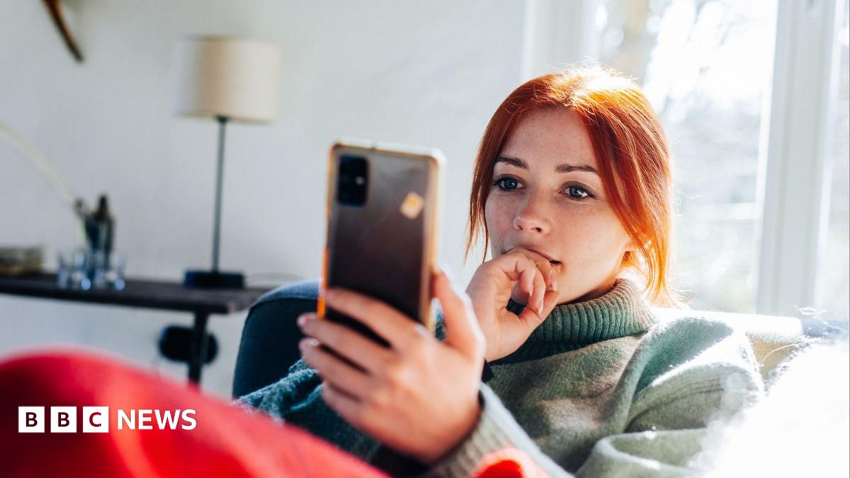 Close up of a young woman in a jumper looking at her mobile phone