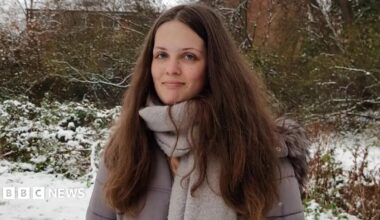 Willow sits in a chair in hospital cuddling a soft toy. She has a tube in her nose and is smiling