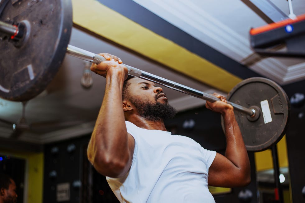 Young man exercising with barbell in gym Man lifting a barbell in a gym setting