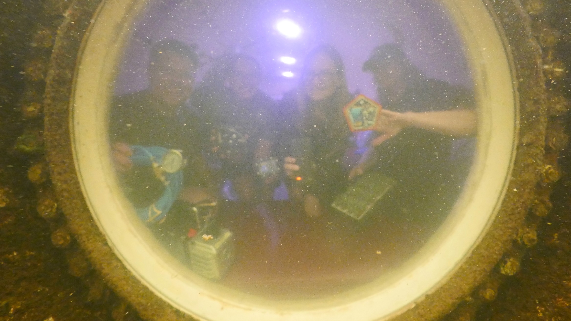 photo of three women and one man, seen fuzzily through a circular porthole
