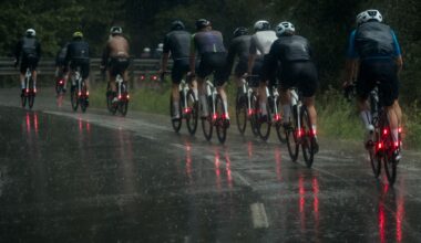 A group of cyclists cycling on a wet road in winter, each of them using winter road bike tyres and with bright red lights on the rear of their bikes