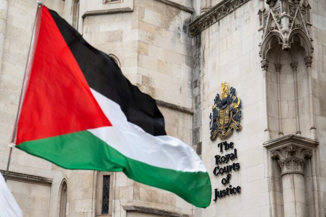 A Palestinian flag is seen held outside the Royal Courts of Justice in London on July 30, 2025. The co-founder of Palestine Action can launch a court bid to overturn the UK government's decision to ban the campaign group under anti-terrorism laws, a High Court judge ruled on July 30. (Photo by Niklas HALLE'N / AFP) (Photo by NIKLAS HALLE'N/AFP via Getty Images)