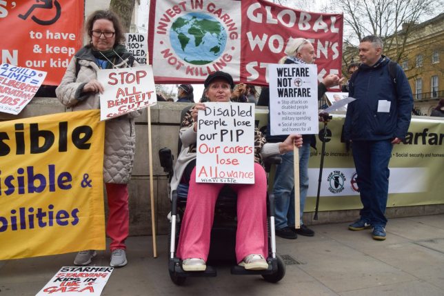 LONDON, UNITED KINGDOM - 2025/03/26: Protesters hold placards in support of Personal Independence Payment (PIP) and welfare outside Downing Street during a demonstration against benefit cuts. Crowds of protesters gathered in Westminster as Chancellor of the Exchequer Rachel Reeves presented her Spring Statement. (Photo by Vuk Valcic/SOPA Images/LightRocket via Getty Images)