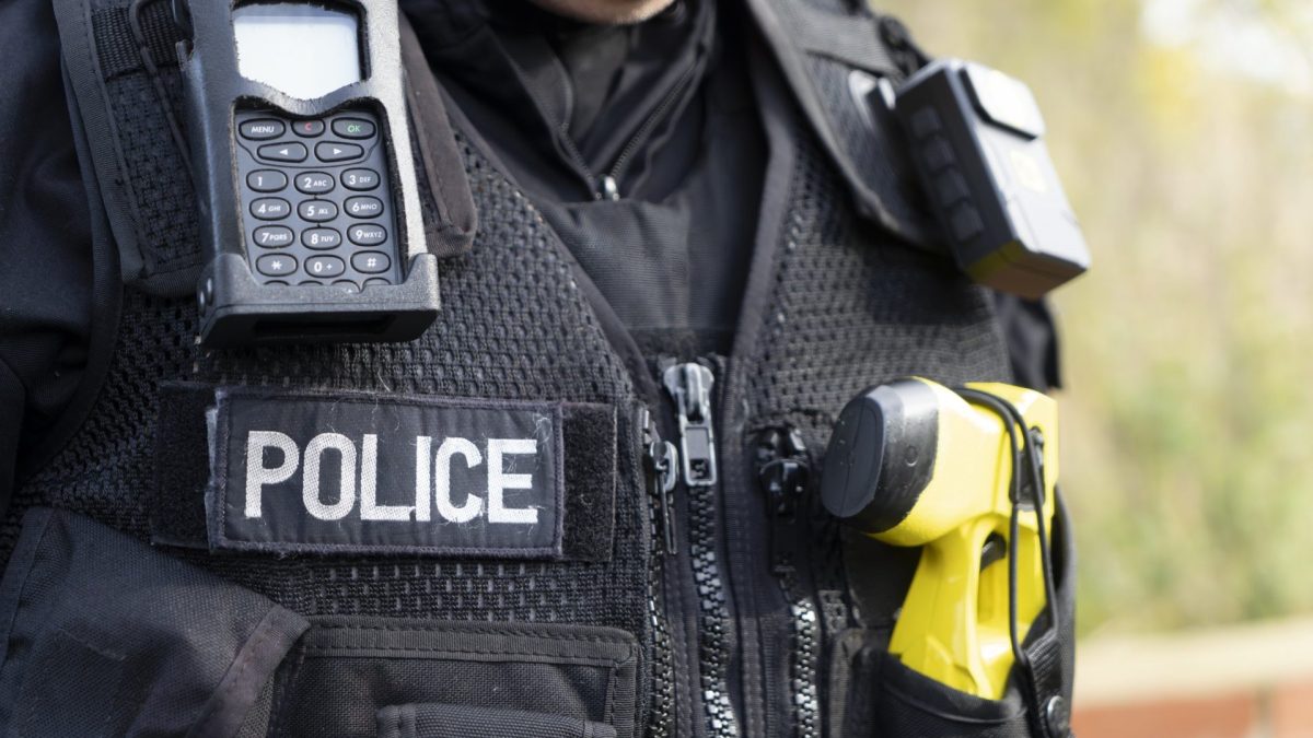 UK police officer with his body camera, taser and police radio attached to his stab vest.