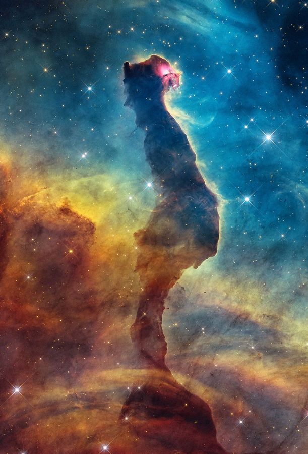 Visible-light image of the Cat’s Head Nebula by the Hubble Space Telescope. A dark brown, opaque filament of dust is in the center, stretching from the bottom to almost the very top. It has a narrow, irregular shape that resembles a cat sitting with its back toward the viewer and a tail extending downward. The cat’s head is turned toward the right, revealing a red glowing eye. The top half of the background is bright blue. Approximately halfway down, cutting diagonally across the frame, the background color changes from blue to yellow, orange, and finally red near the bottom. The image is dotted with many small stars. Some larger stars with the telescope’s characteristic four-point diffraction spikes are scattered in the background and foreground.