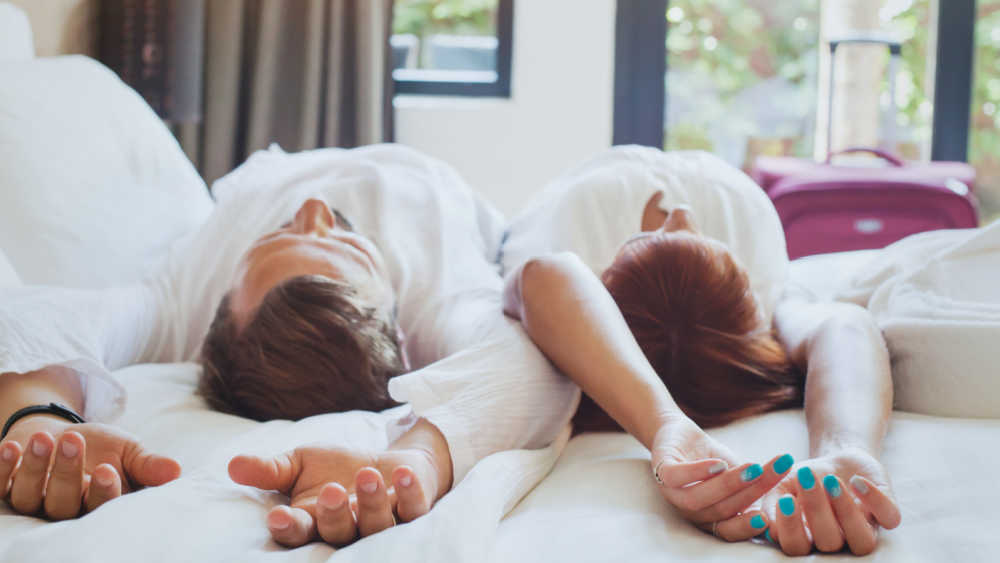 couple resting on top of hotel bed