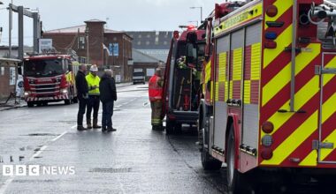 Fire engines parked in a street near the scene of a of a scrap yard fire