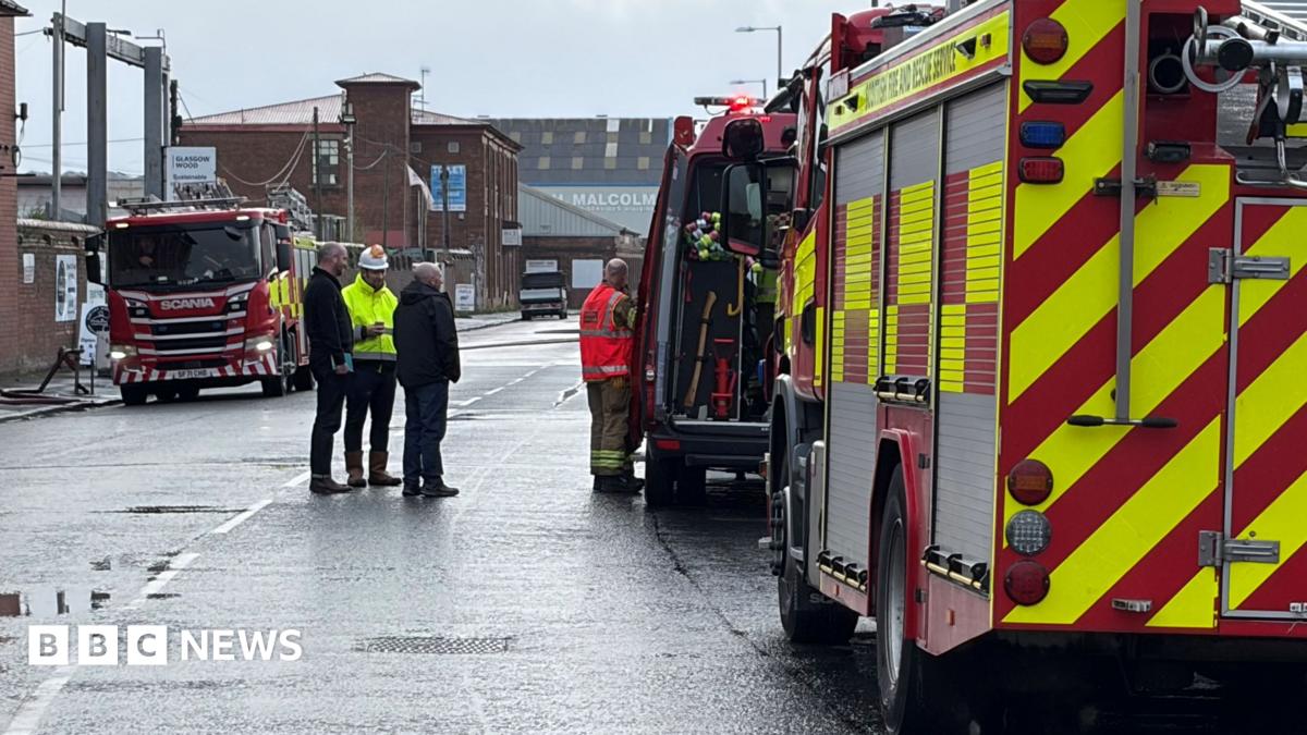 Fire engines parked in a street near the scene of a of a scrap yard fire