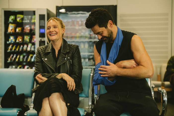 adultery_romola-dominic Romola Garai as Beth and Dominic Cooper as Tom in Adultery sitting in a hospital waiting room, laughing.