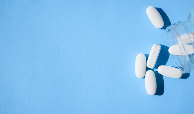 White pills spill out of a pill jar.