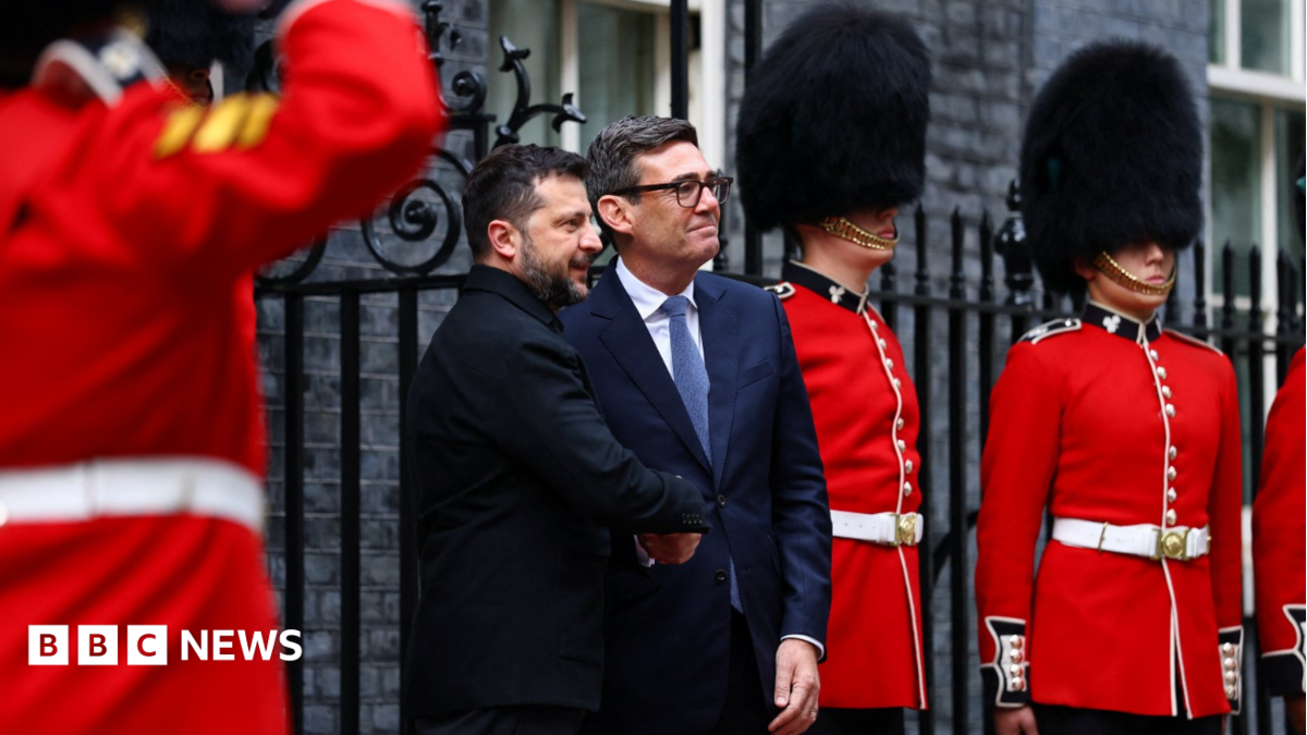 MI5 chief Sir Ken McCallum has short dark hair, dark glasses and is wearing a dark suit with a green tie.