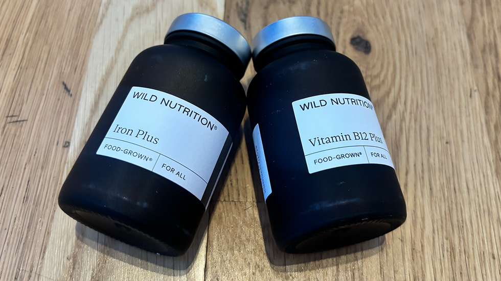 Supplement stacking two black bottles of wild nutrition supplements on wood surface.