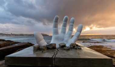 a sculpture of a giant hand breaking through the ground at Bondi Beach, NSW, Australia