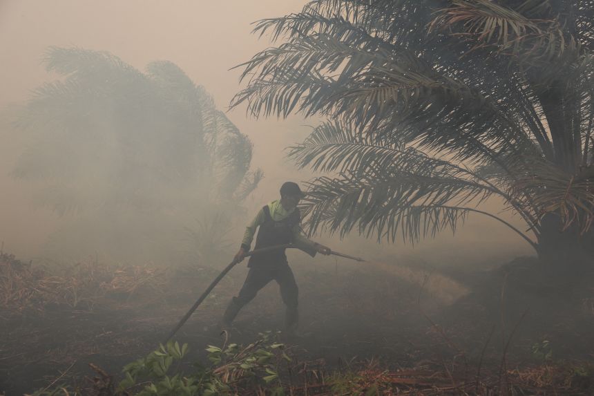 A local farmer extinguishes a fire on his palm oil plantation in Sungai Putri, a wildfire-affected peatland area in Indonesia, on August 29.