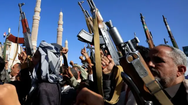Protesters brandish guns into the air at an outdoor protest