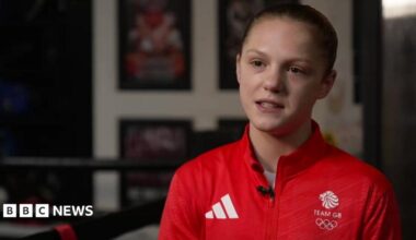 Lily Bassett in a red Team GB sports top in a boxing gym.