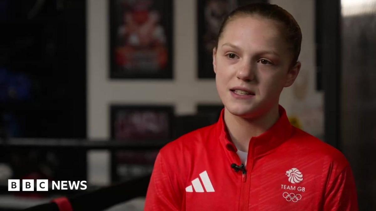 Lily Bassett in a red Team GB sports top in a boxing gym.