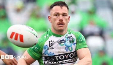 Tom Starling, in Canberra Raiders' white and green shirt, makes a pass