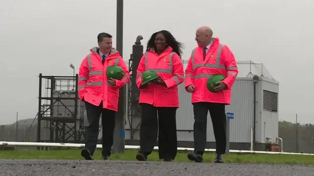 The two walk with another person on a grey day in Aberdeen. They wear high-vis
