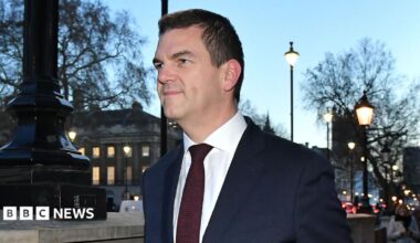 Sir Olly Robbins walking down Whitehall wearing a suit and tie.