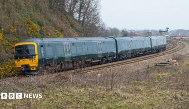 A Great Western Railway Class 165 Diesel Multiple Unit passenger train, with its distinctive green livery. It rounds a long, curved bend on the railway.