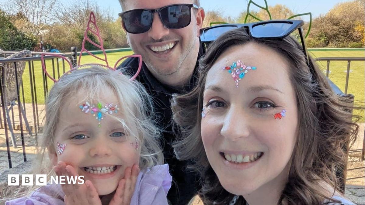 Pictured is Seren, Mark and Clare. Seren has a unicorn headband on, and gems on her face. She is smiling at the camera. She has a purple top on. In the middle, is her dad Mark. He is smiling at the camera and wearing black sunglasses. He has a black top on too. To the right of the photo, is Seren's mum, Clare. She has gems on her face too. She has a green unicorn headband on. She is smiling at the camera, and has curly brown hair.