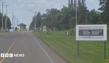 Canadian Forces Base Wainwright entrance at the end of a road, with a sign on the right hand side of the road