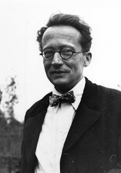 A man with round glasses, dark hair and a bow tie