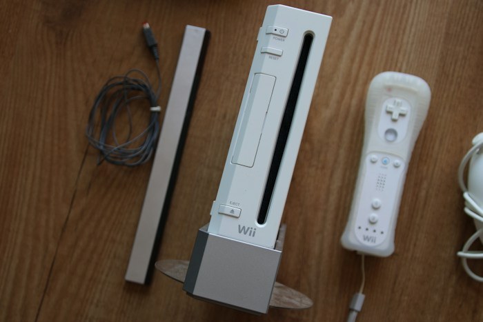 A white Nintendo Wii console with a controller and sensor bar, showing lucky dumpster finds on a wooden floor.