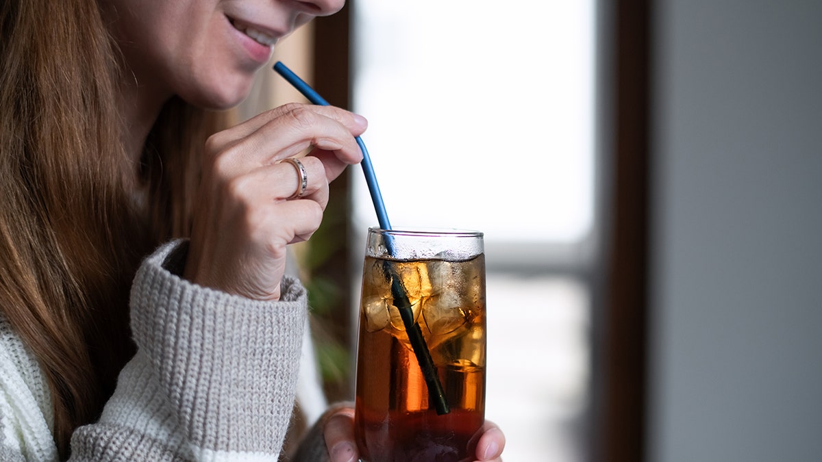 woman drinking soda out of a straw
