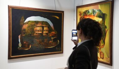 A visitor photographs artworks at the