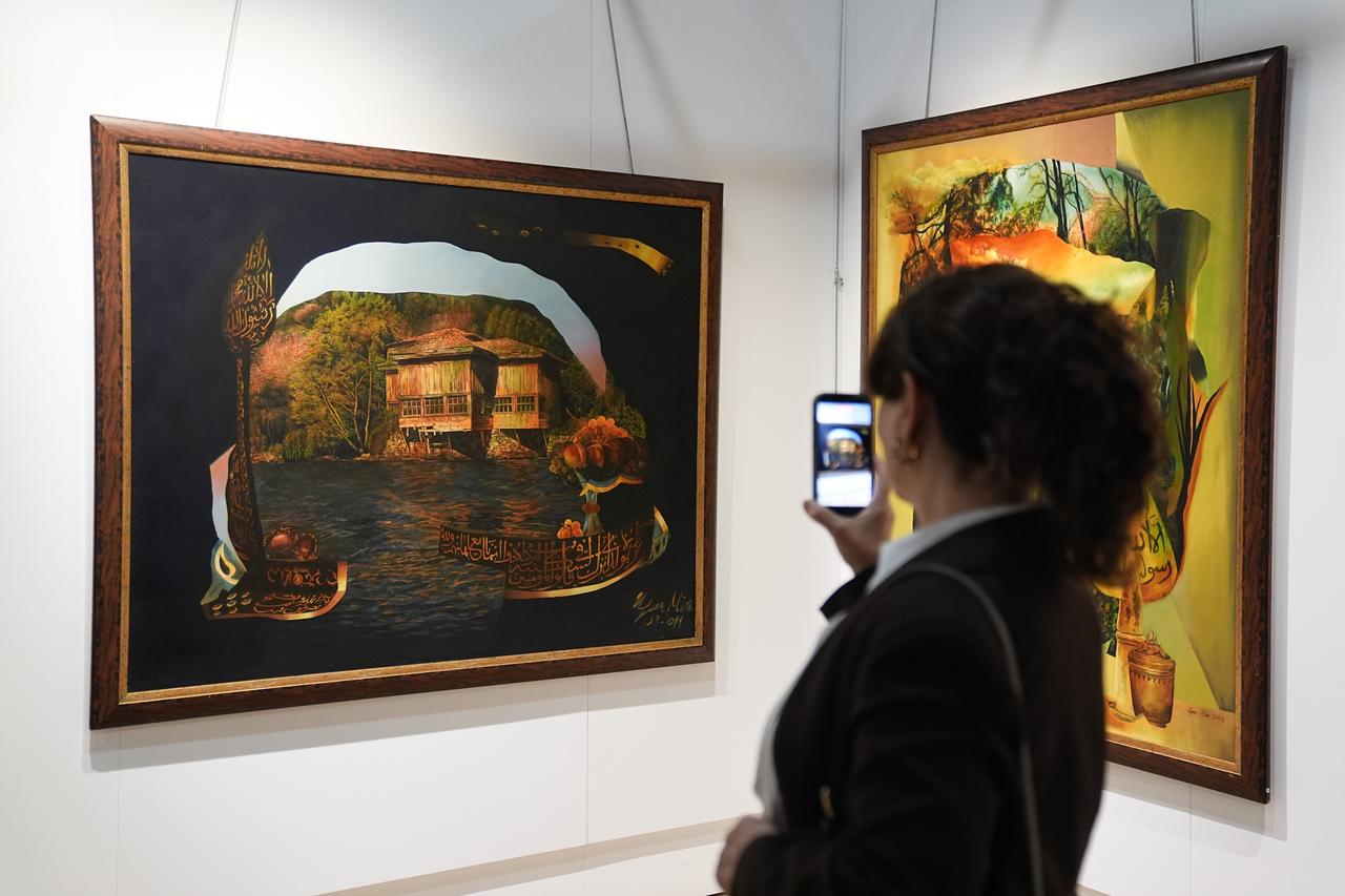 A visitor photographs artworks at the