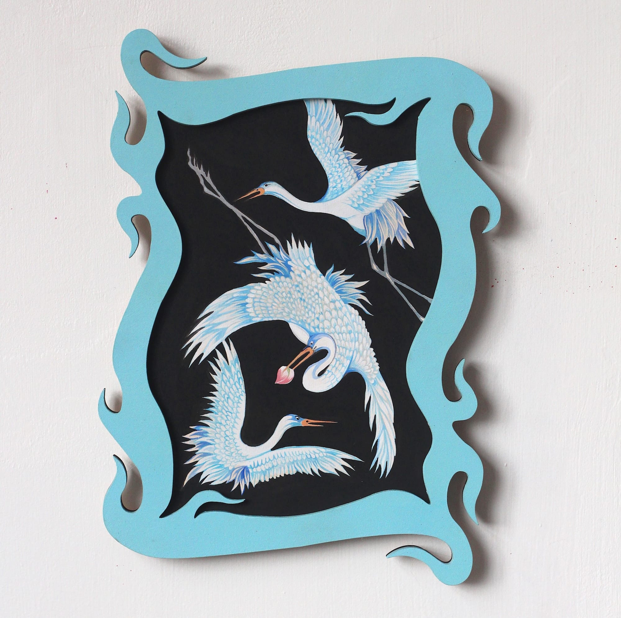 a painting of three cranes on a black background with a swirling, carved, teal-colored wooden frame