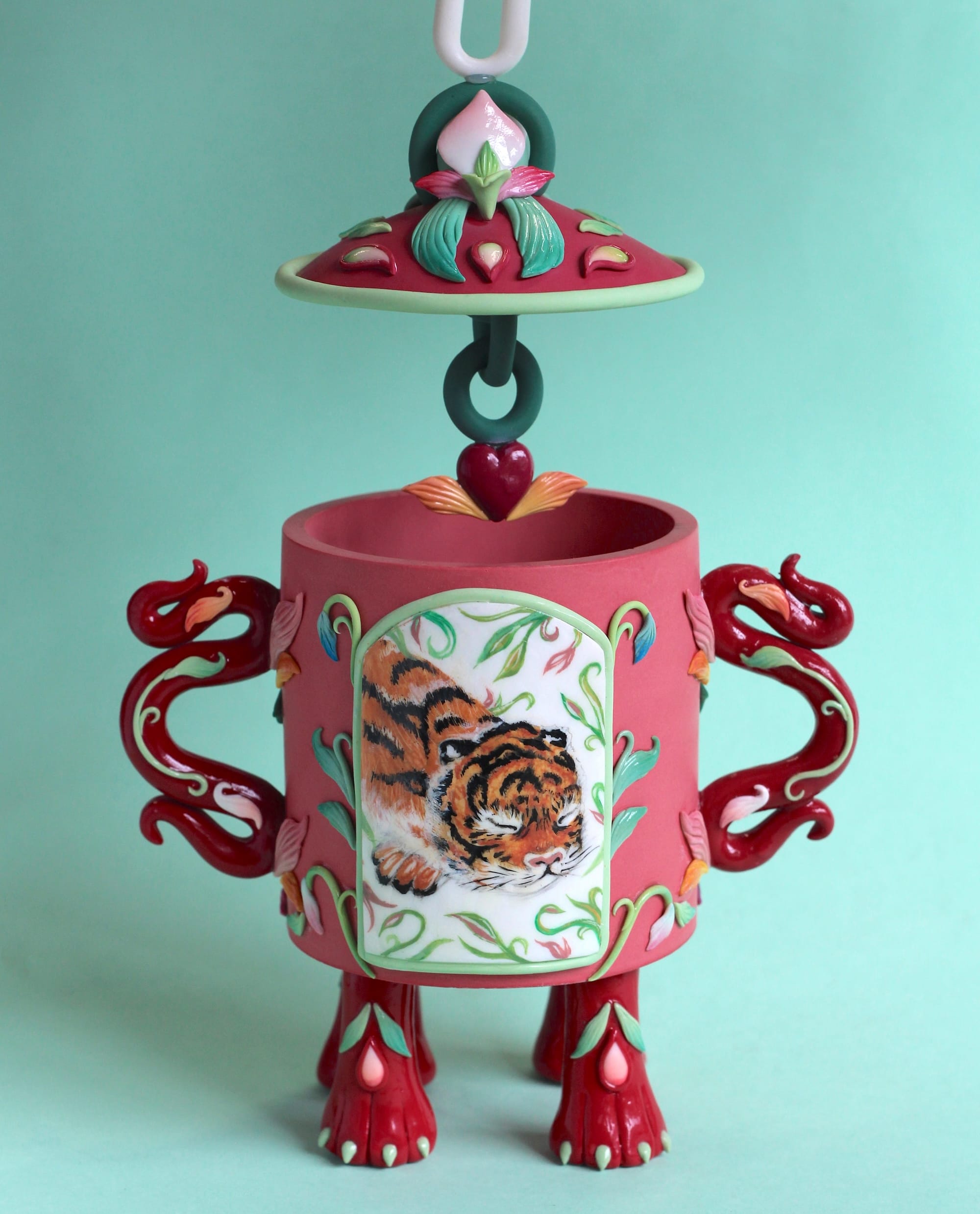 a stylized snuff bottle sculpture made from polymer clay featuring a painting of a small sleeping tiger