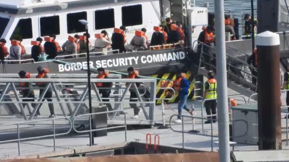 Migrants disembarking from a Border Force vessel
